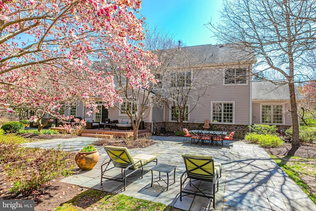 back of property featuring a patio area and stone siding