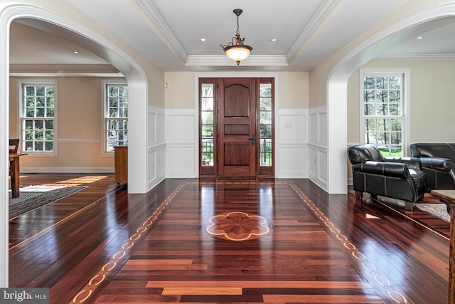 foyer entrance with a decorative wall, arched walkways, and hardwood / wood-style flooring
