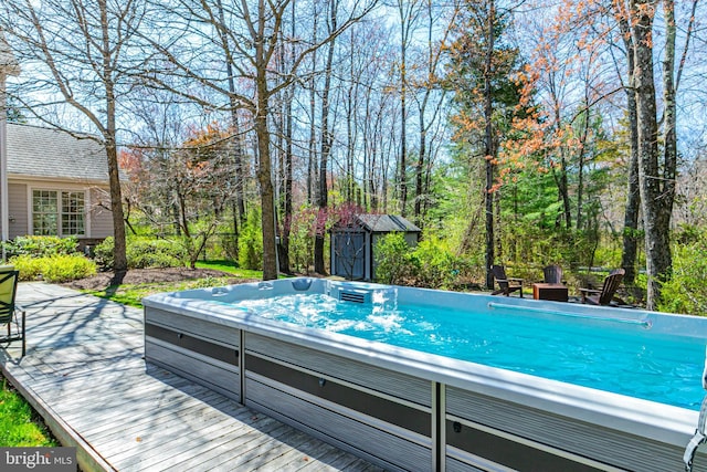 view of swimming pool with a storage shed, an outbuilding, a deck, and a hot tub