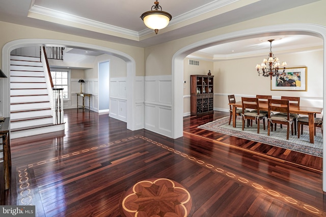 dining room featuring an inviting chandelier, arched walkways, ornamental molding, stairway, and wood finished floors