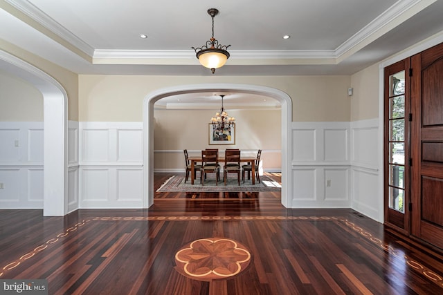 foyer featuring arched walkways, a decorative wall, and wood finished floors