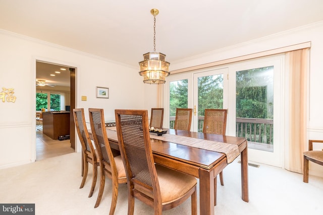 dining area featuring plenty of natural light, crown molding, light carpet, and a chandelier