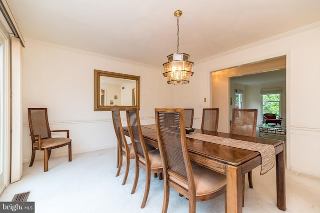 dining space featuring light colored carpet, ornamental molding, and a chandelier