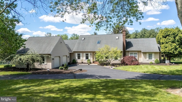 cape cod-style house featuring a garage, driveway, a front yard, and a chimney