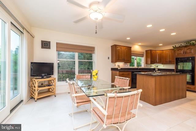 kitchen with black appliances, dark countertops, a kitchen island, recessed lighting, and brown cabinets