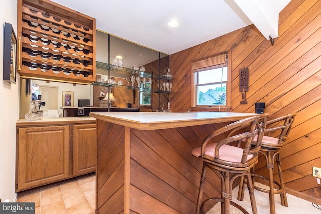indoor wet bar with wood walls and light tile patterned floors