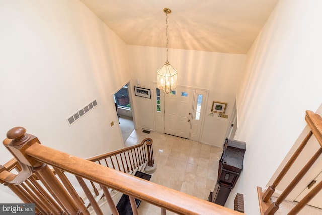 entrance foyer with a chandelier, stairs, a towering ceiling, and light tile patterned floors