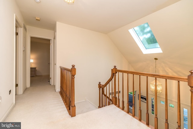 hallway with a skylight, an upstairs landing, light colored carpet, and lofted ceiling
