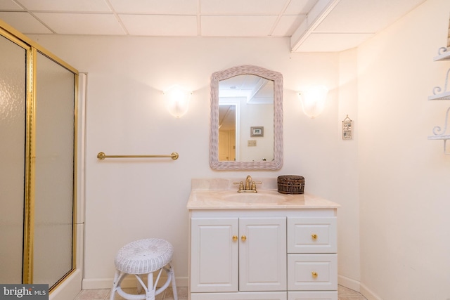 full bath featuring an enclosed shower, vanity, baseboards, and a drop ceiling