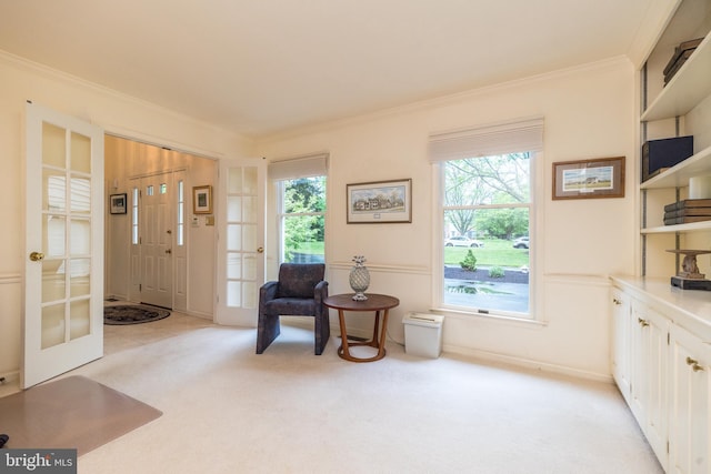 living area featuring french doors, light colored carpet, and ornamental molding