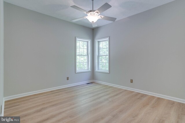 spare room with light wood-style floors, a ceiling fan, baseboards, and visible vents