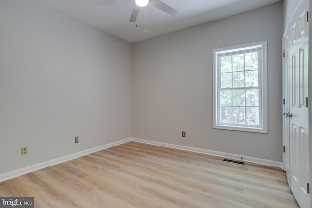 spare room featuring baseboards, ceiling fan, light wood-style flooring, and visible vents