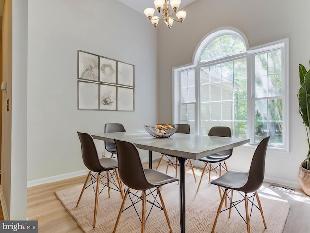 dining space featuring baseboards, a notable chandelier, visible vents, and light wood-style flooring