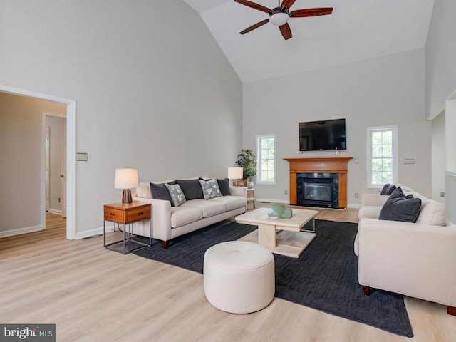 living room with a ceiling fan, high vaulted ceiling, a healthy amount of sunlight, and wood finished floors