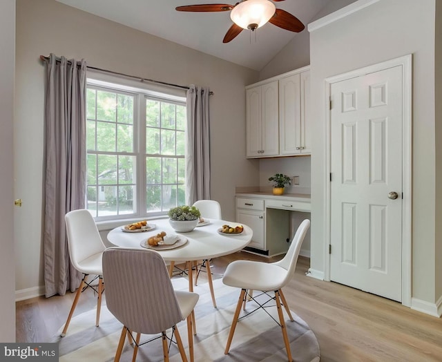 dining area featuring baseboards, a ceiling fan, light wood-type flooring, and lofted ceiling