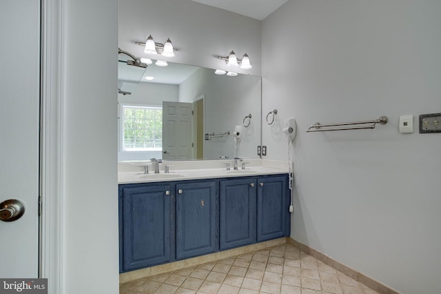 bathroom featuring baseboards, double vanity, tile patterned floors, and a sink