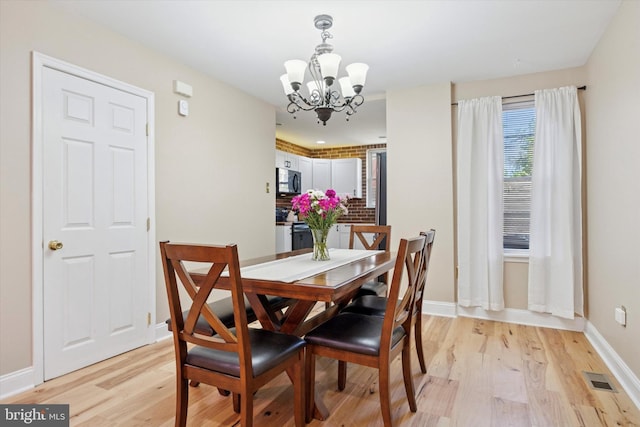 5223 Pentridge St, Philadelphia, PA 19143 - dining area featuring a chandelier, light wood-style flooring, and baseboards