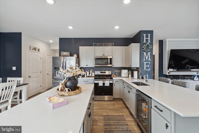 kitchen with a peninsula, light countertops, a sink, stainless steel appliances, and wine cooler