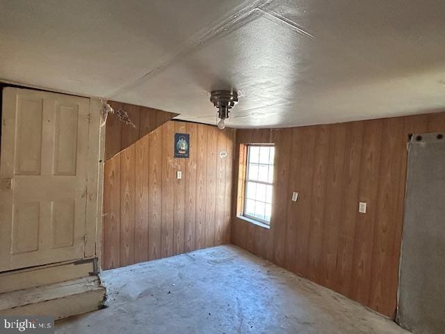 unfurnished room featuring wood walls and concrete flooring