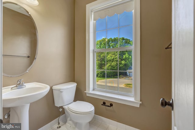 bathroom featuring baseboards, tile patterned flooring, and toilet