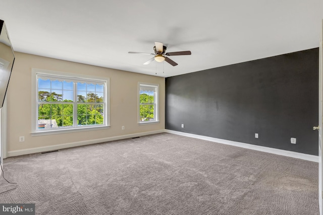 carpeted spare room with baseboards, ceiling fan, and visible vents