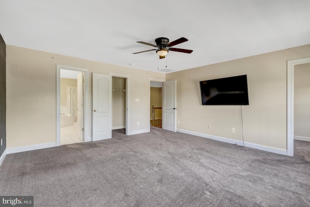unfurnished bedroom with baseboards, a walk in closet, carpet, and a closet