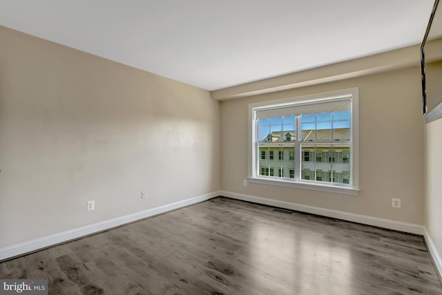 spare room featuring baseboards, wood finished floors, and visible vents