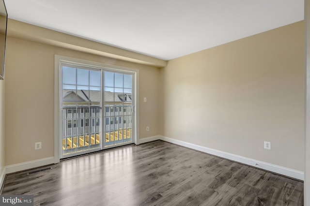 unfurnished room featuring baseboards, wood finished floors, and visible vents