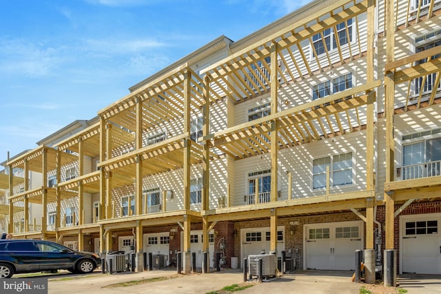 view of property with central air condition unit, an attached garage, and driveway