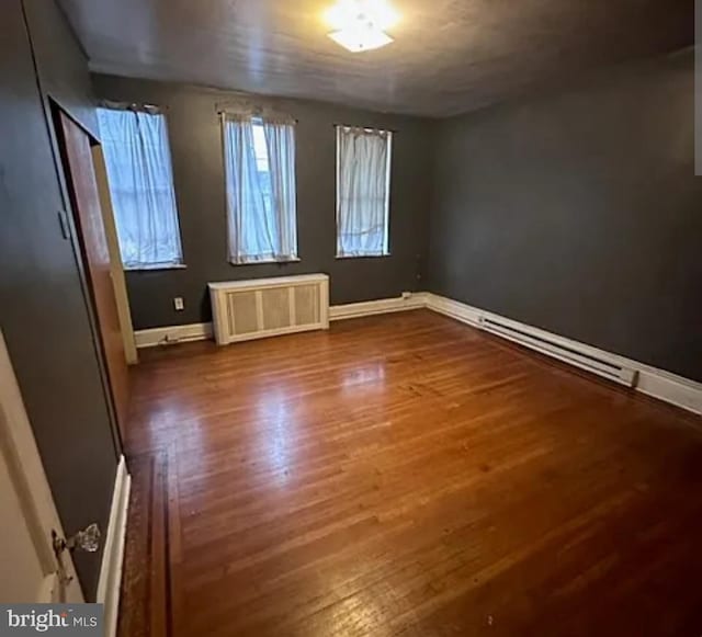 1911 Mckean St, Philadelphia, PA 19145 - empty room with a baseboard radiator, wood finished floors, radiator heating unit, and baseboards