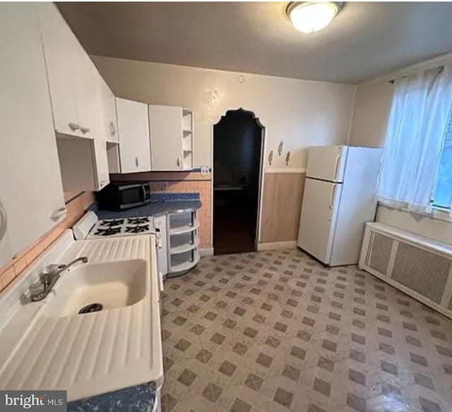 1911 Mckean St, Philadelphia, PA 19145 - kitchen featuring white appliances, white cabinetry, open shelves, radiator heating unit, and a sink
