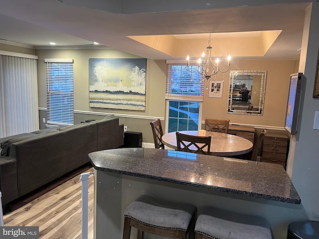 1646 Mcnelis Dr, Southampton, PA 18966 - kitchen with dark stone countertops, a chandelier, light wood-style floors, a kitchen bar, and a tray ceiling