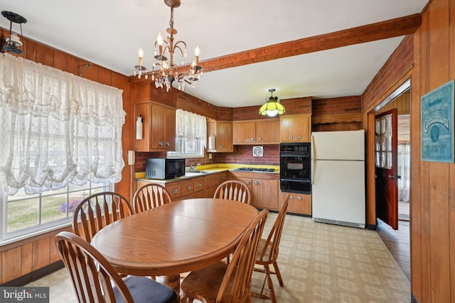 dining room with beamed ceiling, wooden walls, and a notable chandelier