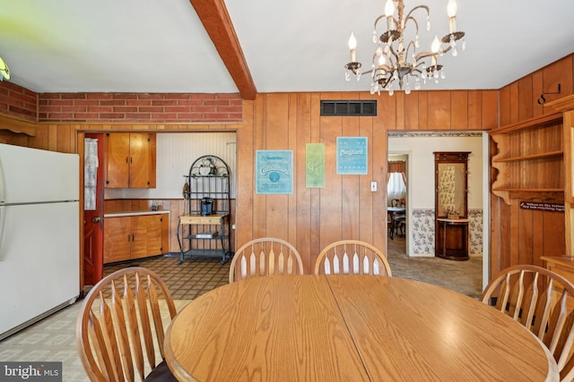 dining space with wooden walls, an inviting chandelier, and visible vents