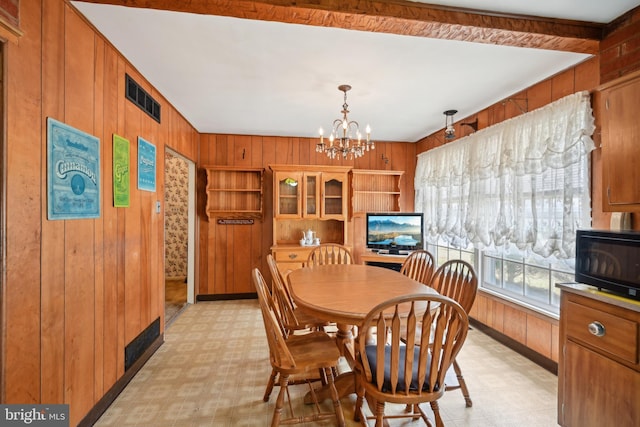 dining space with light floors, wooden walls, visible vents, baseboards, and a chandelier