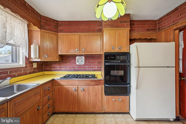 kitchen featuring a sink, gas cooktop, a warming drawer, black oven, and freestanding refrigerator