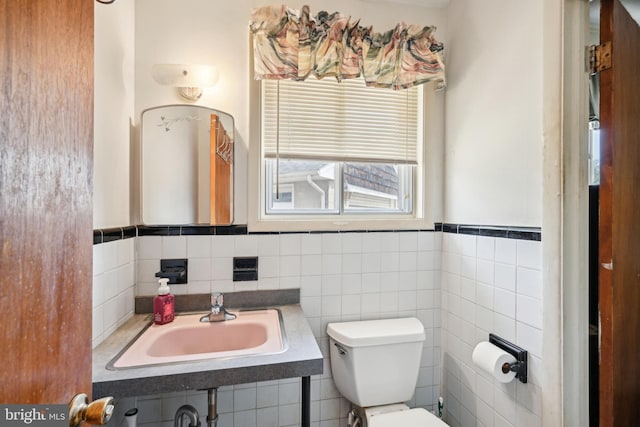 bathroom featuring toilet, a wainscoted wall, and a sink
