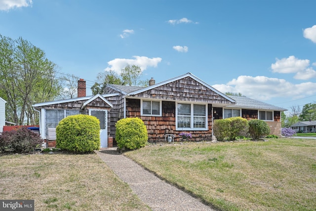 ranch-style house featuring a chimney, roof with shingles, and a front yard