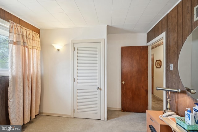 bedroom featuring wooden walls, visible vents, and light colored carpet