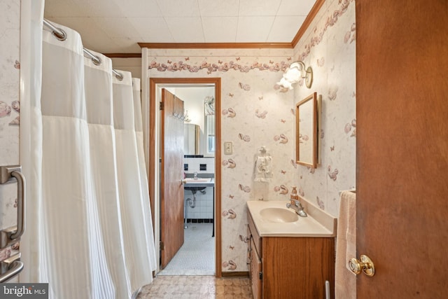 full bath featuring a shower with shower curtain, wallpapered walls, crown molding, and vanity