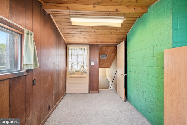 hallway featuring carpet, lofted ceiling, wood ceiling, and wood walls