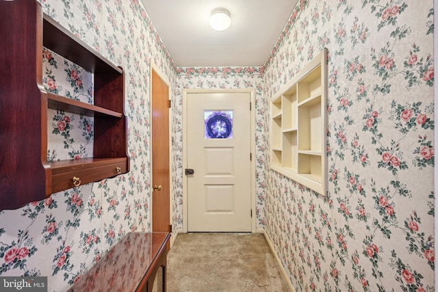 doorway to outside with wallpapered walls and carpet flooring