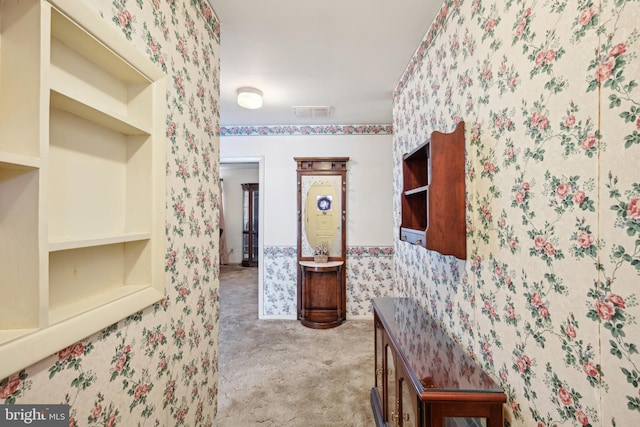 hallway featuring wallpapered walls, visible vents, and carpet floors
