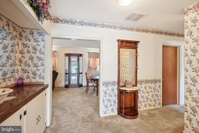 hall featuring light carpet, wallpapered walls, and visible vents