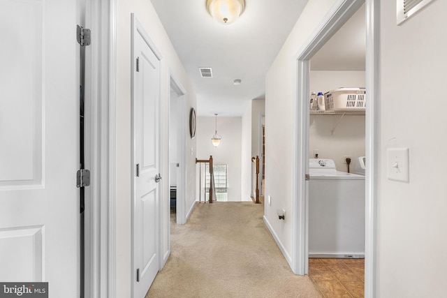 corridor with visible vents, independent washer and dryer, an upstairs landing, and light colored carpet