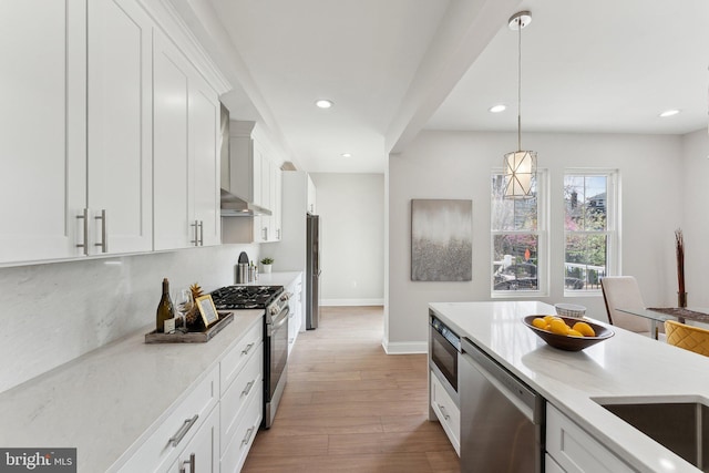 5707 Colorado Ave NW, Washington, DC 20011 - kitchen featuring wall chimney exhaust hood, stainless steel appliances, white cabinets, wood finished floors, and hanging light fixtures