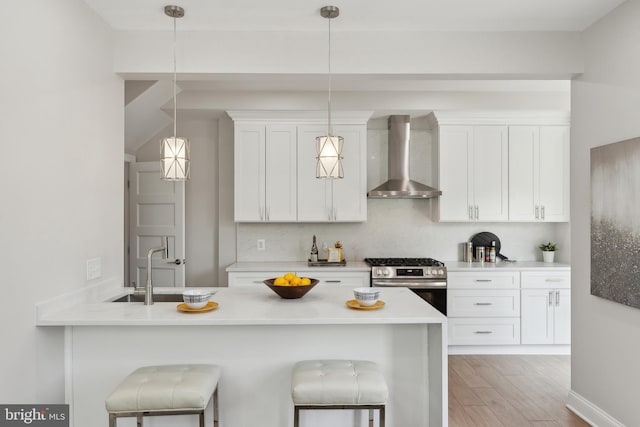 5707 Colorado Ave NW, Washington, DC 20011 - kitchen featuring wall chimney exhaust hood, stainless steel range with gas cooktop, white cabinets, and light wood-type flooring