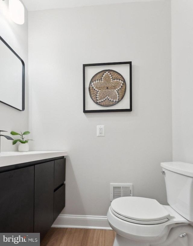 5707 Colorado Ave NW, Washington, DC 20011 - half bath featuring wood finished floors, vanity, baseboards, toilet, and visible vents