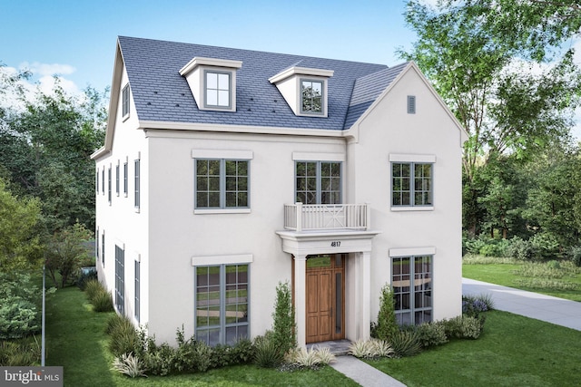 view of front of home featuring a high end roof, a front lawn, a balcony, and stucco siding