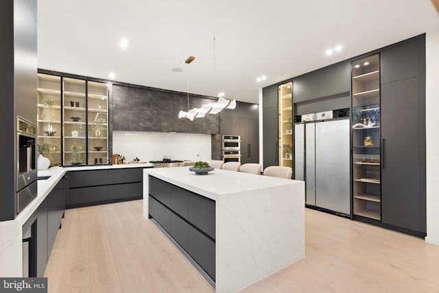 kitchen with a center island, light wood-style floors, stainless steel appliances, and modern cabinets